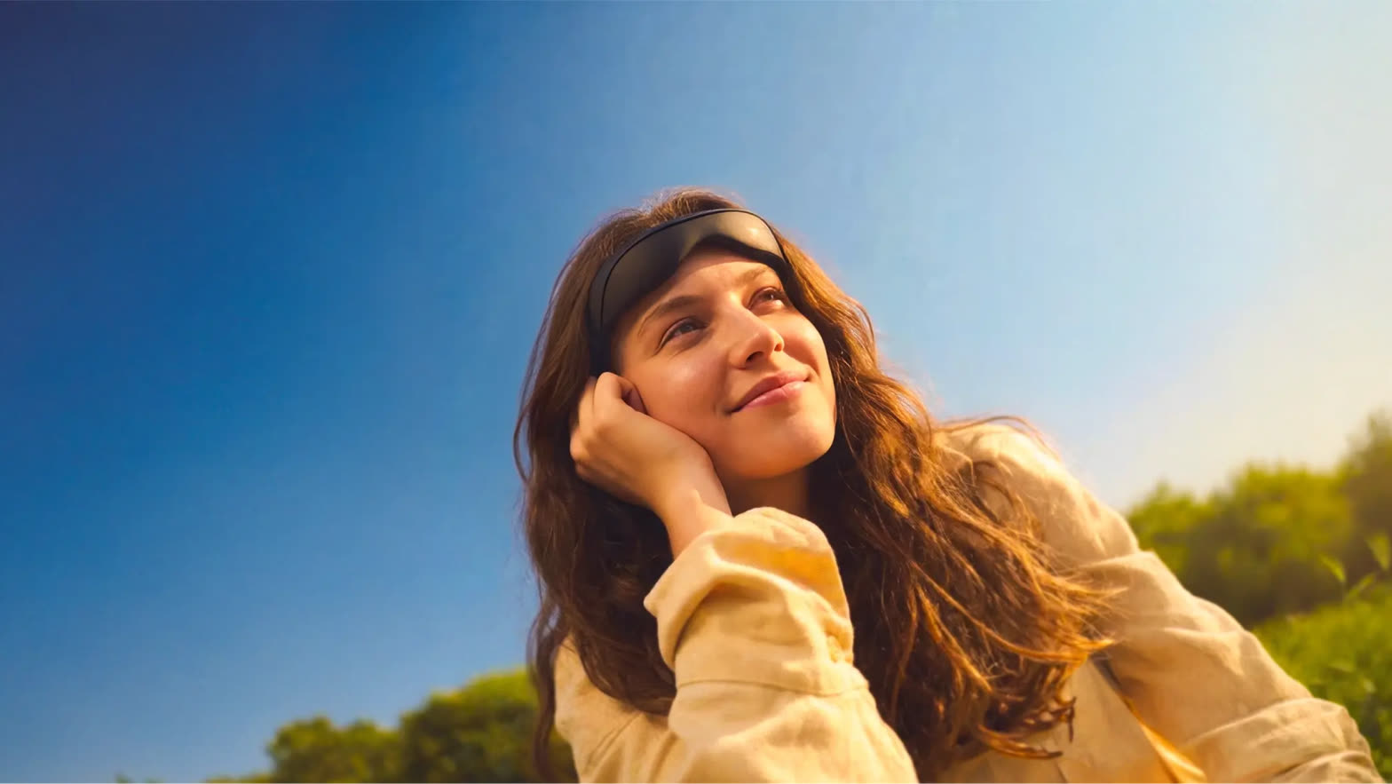 A woman wearing the Mave headset, smiling in the sun